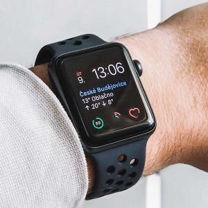 Smartwatch on a wrist displaying time and weather information against a light background