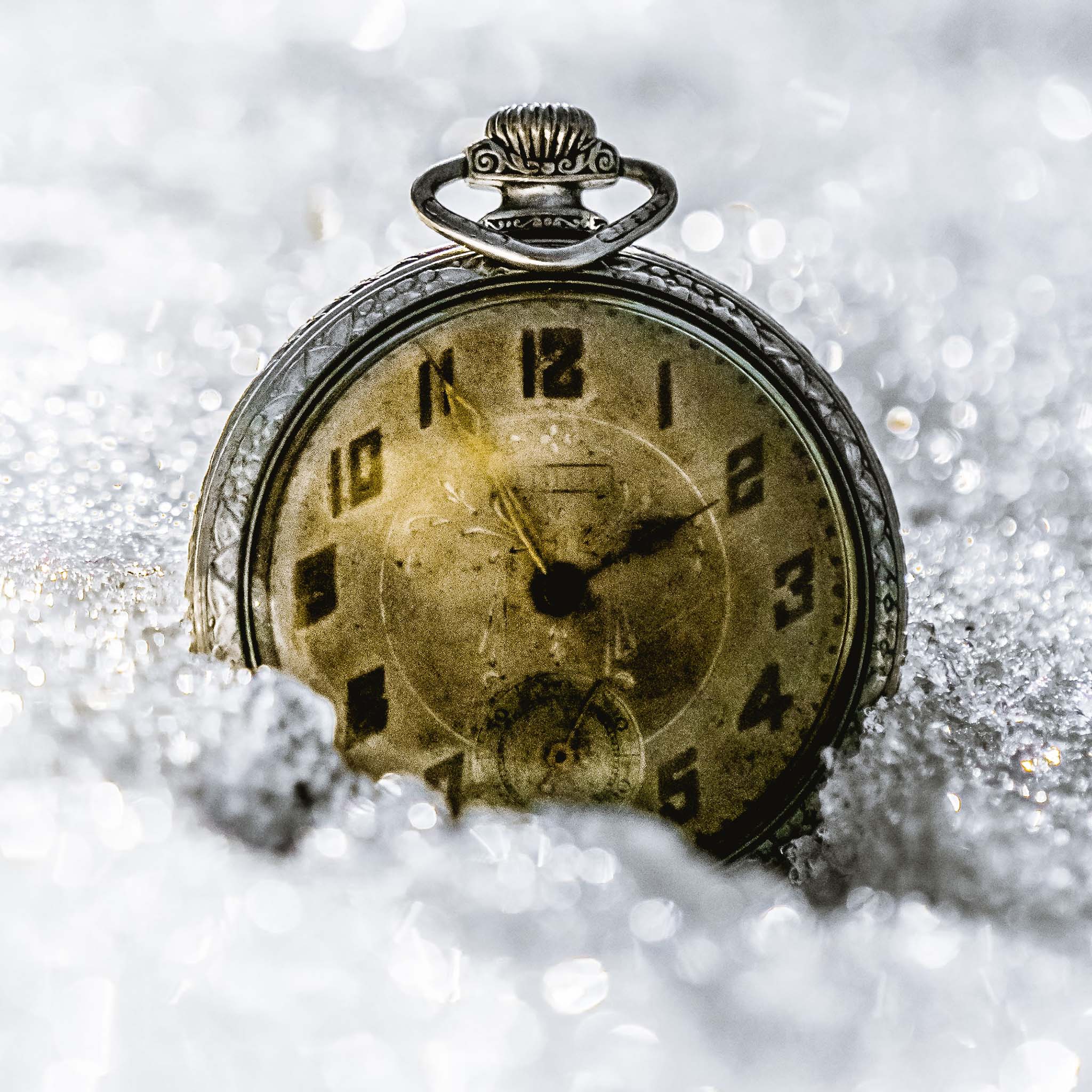 Vintage pocket watch partially submerged in snow
