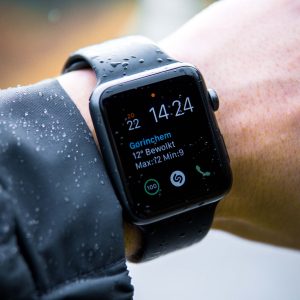 Smartwatch on a wrist with weather app display, worn in rain