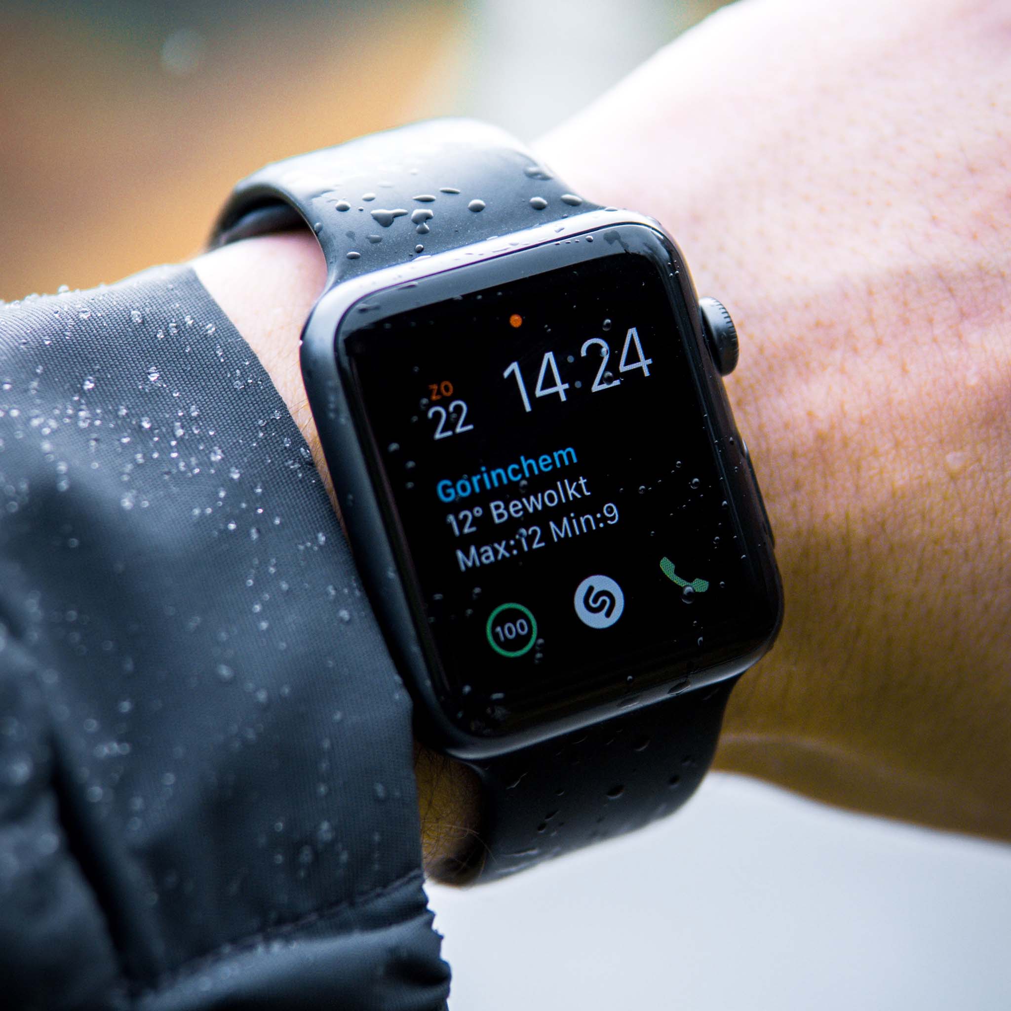 Smartwatch on a wrist with weather app display, worn in rain