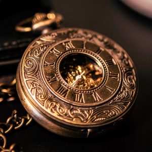 Close-up of a gold pocket watch with intricate designs on a dark background