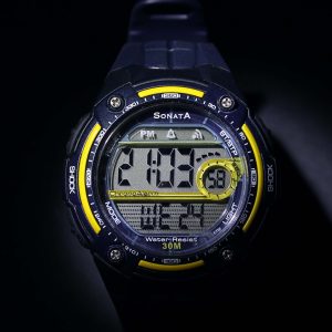 Digital watch with blue and yellow casing on a dark background