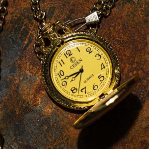Gold pocket watch with a visible brand name on a textured surface