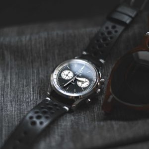 Black watch with a textured surface and sunglasses on a dark fabric background